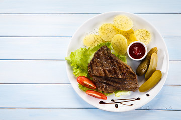 Grilled steaks, boiled potatoes and vegetable salad 