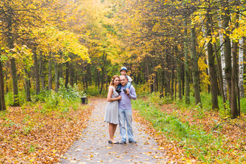 Fototapeta premium Young family for a walk in the autumn park with baby