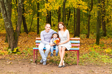 Naklejka na ściany i meble Young family for a walk in the autumn park with baby