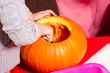 Mädchen nimmt einen Kürbis aus, bastelt eine Jack-o-Laterne für Halloween