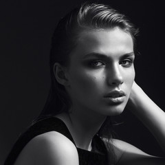 Black and white portrait of a beautiful girl in the studio on a black background, the concept of...