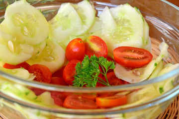 Healthy vegetable salad with cucumber and tomatoes in the glass bowl 