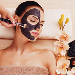 Cosmetologist smears cosmetic mask on the face of  woman