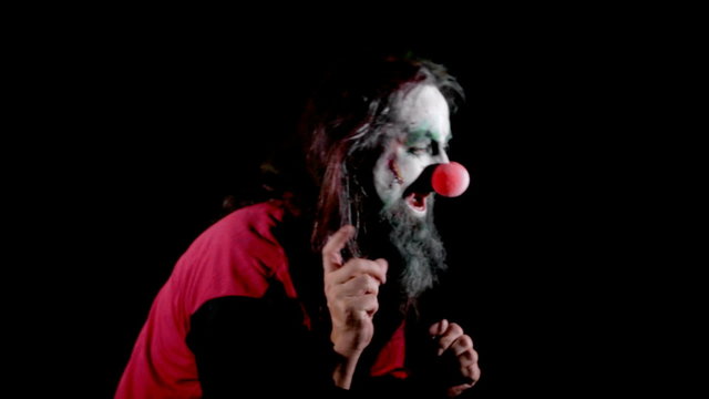male creepy clown in front of black, dancing and showing into empty space