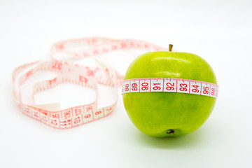 Green apple with measuring tape around on white background