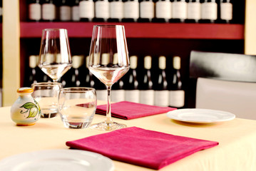 table setting for two against wine cellar