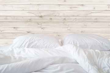 Fototapeta na wymiar White bedding sheets and pillow on wooden wall room background,