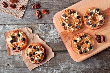 Autumn apple rounds with peanut butter, chocolate chips and nuts, downward view on rustic wood