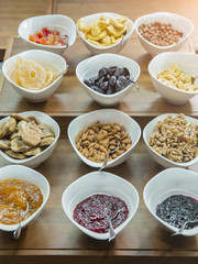 Cereals, nuts and jams in bowls on a wooden table at a hotel breakfast buffet