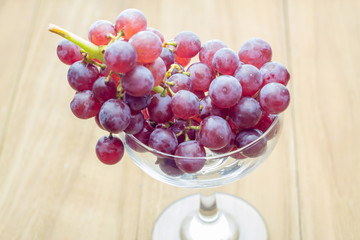 red bunch grape in glass on wooden board