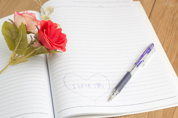 i love you text in notebook with pen and fake flower
