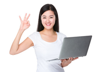 Young woman use of the notebook computer with ok sign gesture