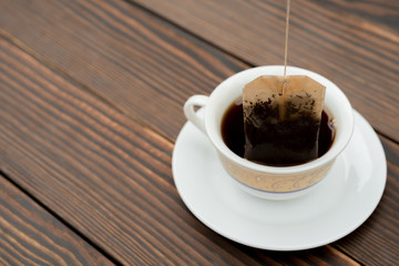 cup of tea with teabag on a wooden background