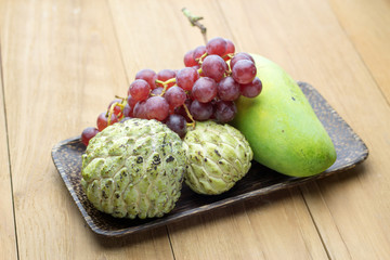 custard apple mango and red grape in wood plate