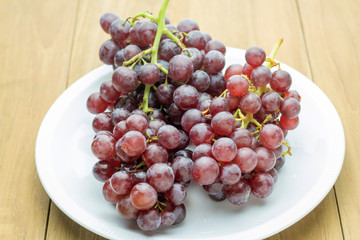red bunch grape in white dish on wooden board