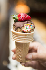chocolate ice cream in cone with fresh strawberry on top