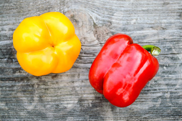 Two ripe sweet peppers on the old gray wooden board