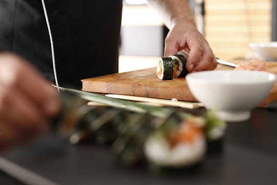 Restauracja japońska, sushi. Sushi z łososiem, krewetką i ogórkiem przygotowywane przez kucharza