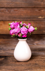 pink roses in a vase on wooden background. flowers
