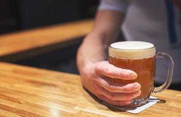 Fototapeta na wymiar Man holding a glass of craft beer in pub
