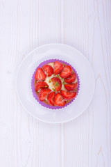 cake with strawberries and custard on a white plate . on a light wooden background. top view. Portion pastries