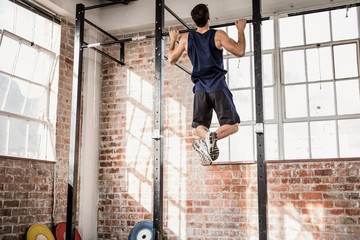 Rear view of muscular man doing pull ups