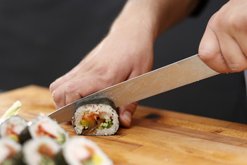 Rolka sushi. Sushi master kroi nożem rolki sushi