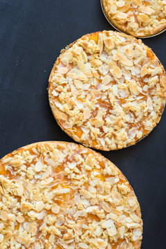 Homemade tarts with apricot jam and almond slices baked in different sizes