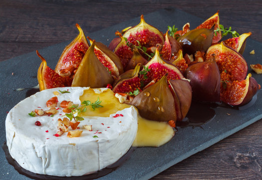 Baked Camembert with figs, hazelnuts and thyme, closeup on dark background