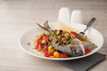Fried dorado with vegetables on the ceramic plate with fork