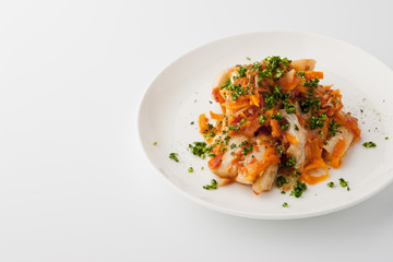 Fish with carrot and greens on the white ceramic plate