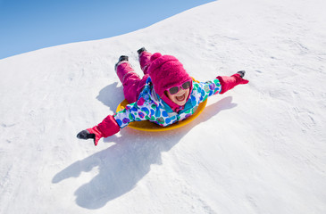 little girl riding on snow slides in winter time - 92647641