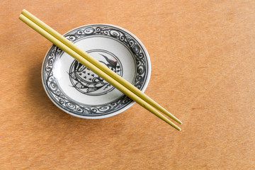 Yellow chopsticks on old dish wooden background