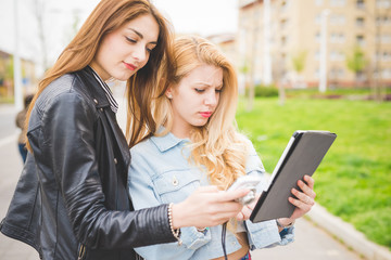 Half length of two young blonde and brunette girls walking throu