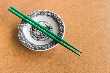 Green chopsticks on old dish wooden background