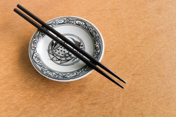 Black chopsticks on old dish wooden background