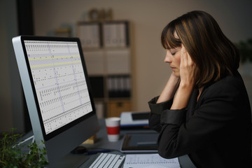 frau im büro arbeitet bis spät am abend und hat kopfschmerzen