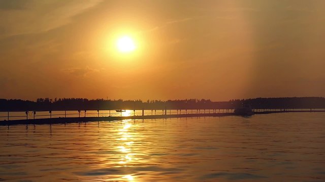 Sunset over the sea. Pier on the foreground in slowmotion