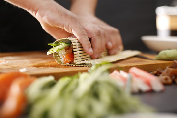 Etapy tworzenia sushi, skręcanie rolki sushi w matę bambusową - obrazy, fototapety, plakaty