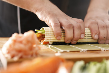 Dłonie kucharza przygotowującego sushi