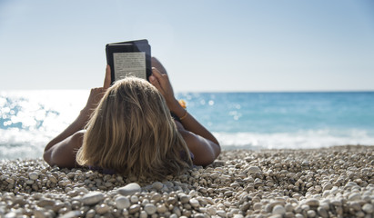 Young woman reading a ebook at beach, relax!