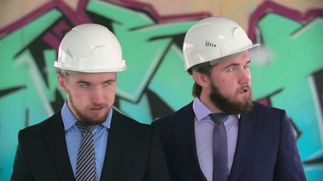 Close-up of two twin architects in helmets shaking heads in slow motion