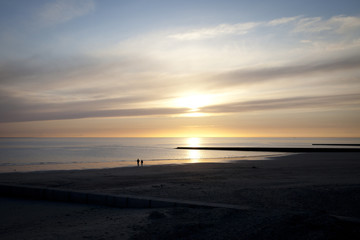 Fototapeta na wymiar two persons enjoy sunset light on the ocean