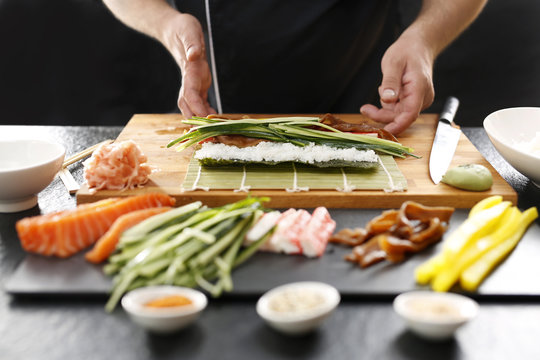 Sushi , etapy przygotowywania sushi z łososiem, paluszkiem krabowym, og&oacute;rkiem tykwą zawiniętego w glon nori