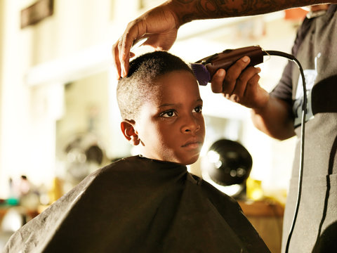 little african boy getting his hair cut in barber shop