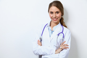 Fototapeta premium Friendly smiling young female doctor, standing near wall