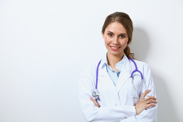 Fototapeta premium Friendly smiling young female doctor, standing near wall