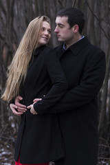 young couple in black coat looking to each others face