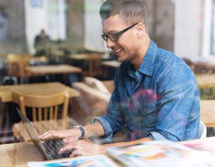 Young man using laptop at cafe