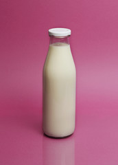 Glass of milk on color pink background